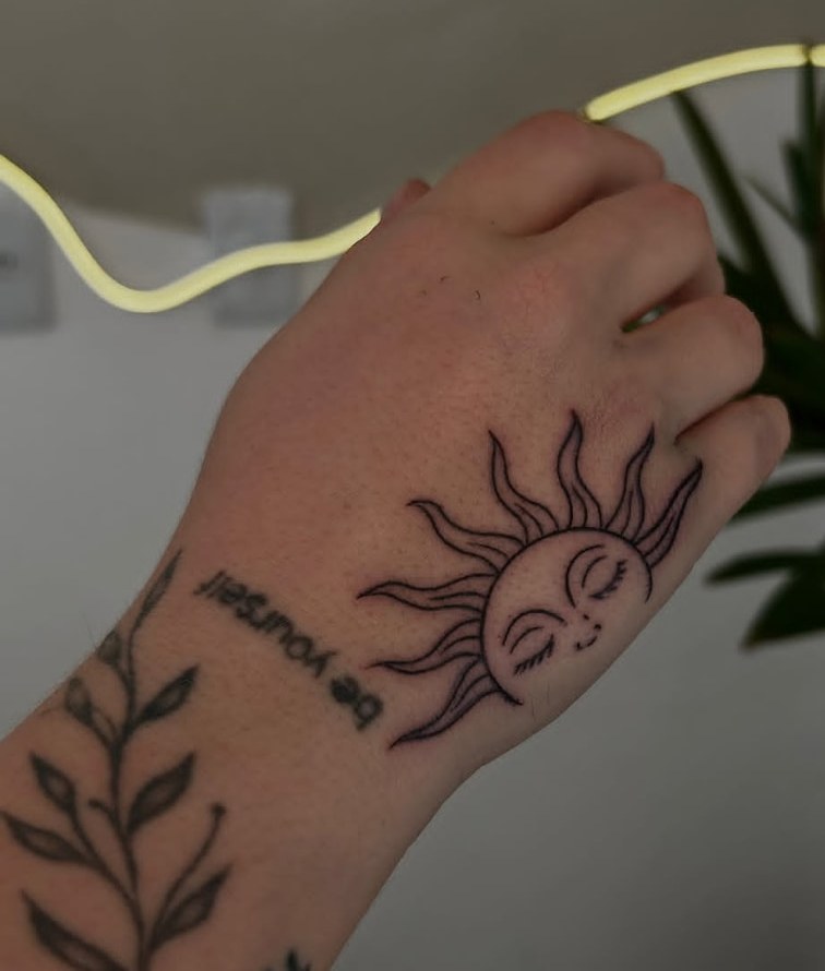 Tatuagem de sol em traço fino na mão